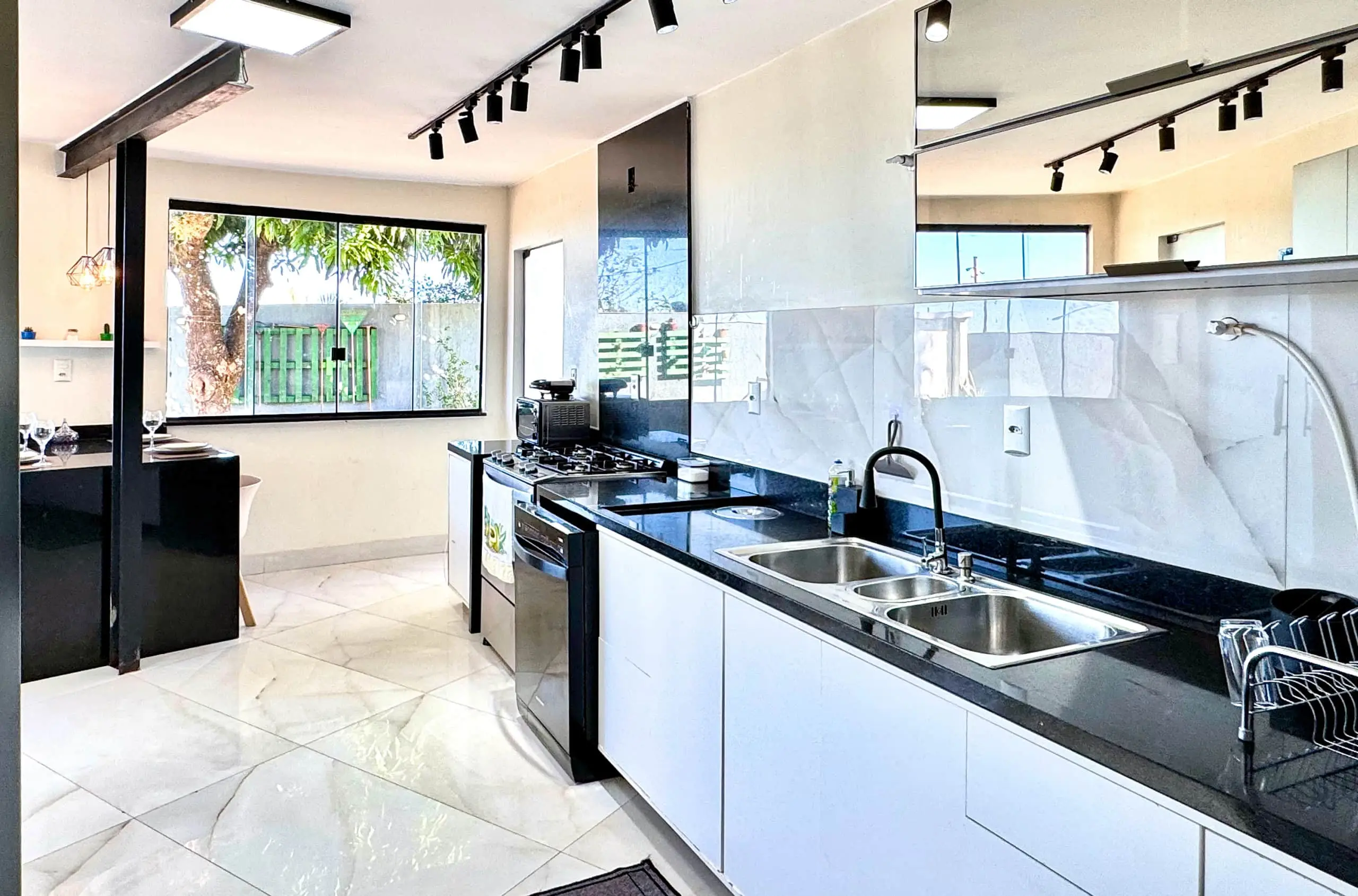 Cozinha equipada, com bancada em granito escuro, cooktop e churrasqueira em destaque.