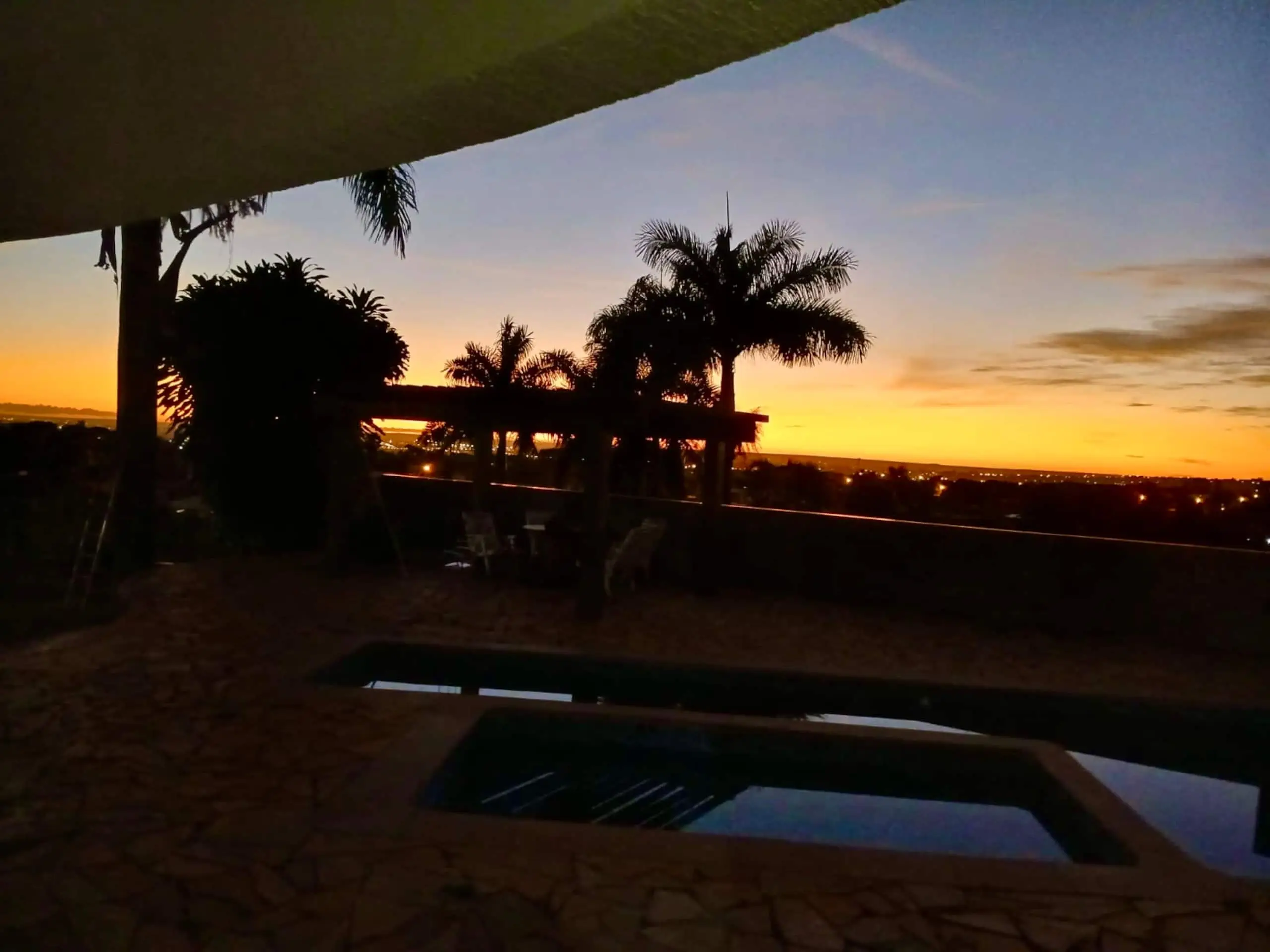 Área externa da Casa Redonda, com deck de pedra e vegetação tropical.