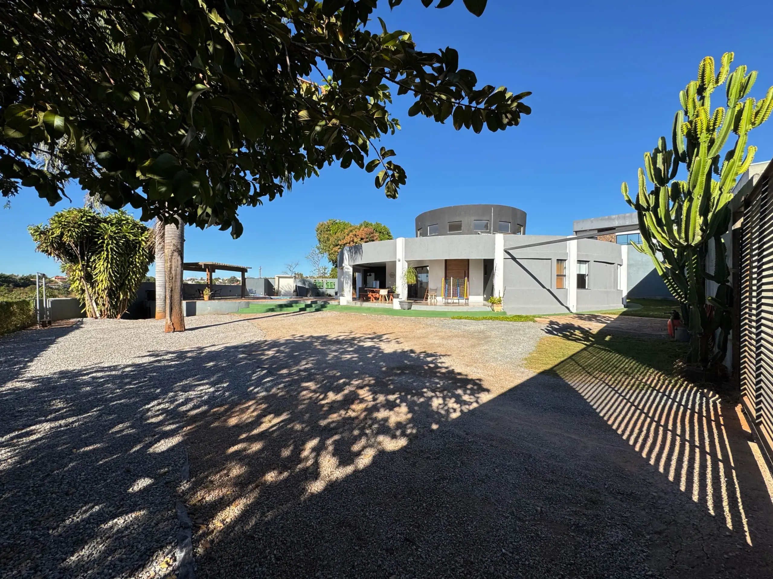 Área externa da Casa Redonda, com deck de pedra e vegetação tropical.